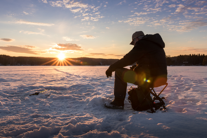 Man ice fishing at sunrise